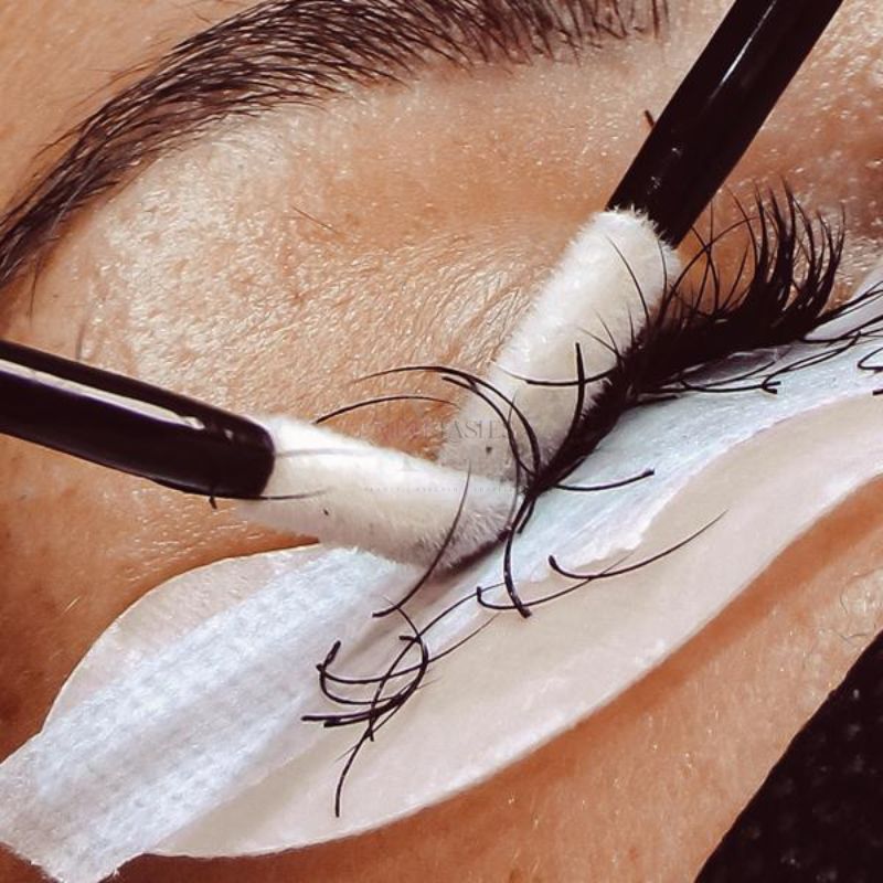 Lint-free micro applicator being used during an eyelash extension procedure for precision application.