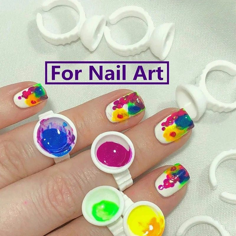 Plastic ring cup used for nail art color mixing, worn on finger for convenience and precision.