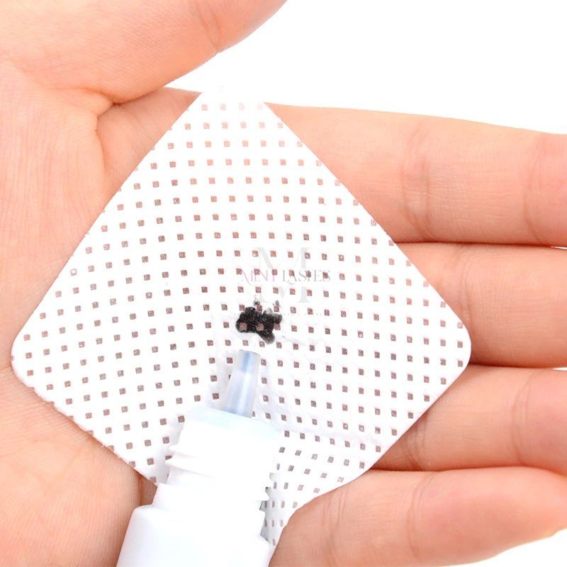 Eyelash glue residue on bottle nozzle being cleaned with a professional tweezers cleanser pad